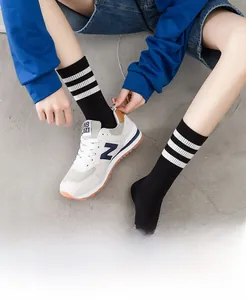 Detail of knit black crew socks with triple white stripes on the ribbed elastic cuff