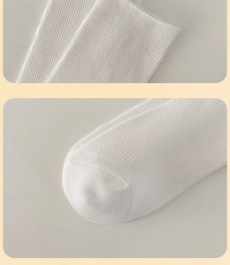 Detail of white rib-knit cotton socks showing the elastic cuff and seamless toe stitching
