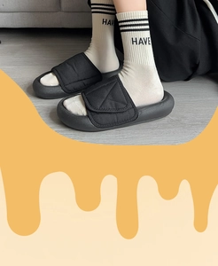 Close-up of black quilted puffer slippers with thick soles on model for cozy style