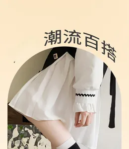 Detail of ruffled cuffs with black wave trim on a white blouse paired with a black dress
