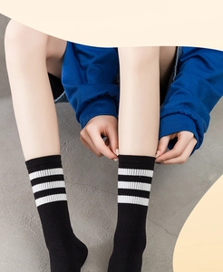 Close-up of black cotton crew socks with three white stripes and elastic ribbing detail