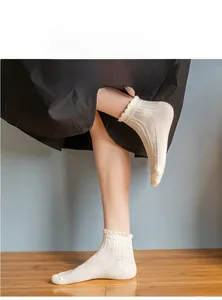 Detailed view of white cotton ankle socks with hollow mesh texture and frill edge cuffs