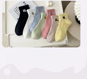 Flat lay of ribbed cotton ankle socks in seven pastel colors with H embroidery detail