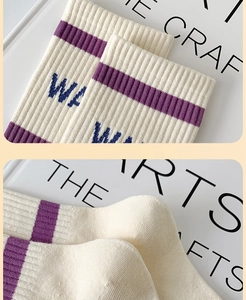 Detail of cream cotton socks featuring purple stripes and blue letter embroidery