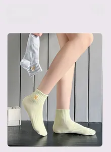 Detail of ribbed knit women's ankle socks featuring golden 'H' letter embroidery