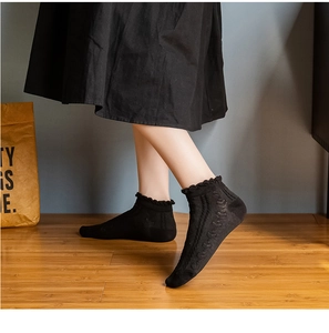 Close-up of black cotton ankle socks featuring delicate ruffle lace trim and ribbed texture