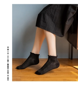 Detail of black ankle socks with ruffle trim and hollow heart patterns for women