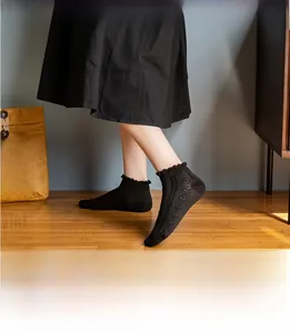 Detail of black cotton ankle socks with ruffle cuffs and wavy knit pattern on a model