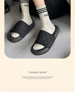 Close-up of black quilted slides worn with white cotton socks and thick soles