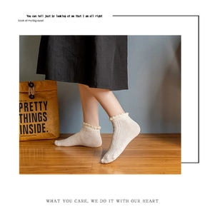 Detailed view of white cotton socks with jacquard heart patterns and ruffled edges