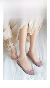 Detail of purple low-cut invisible liner socks worn on feet over white fabric