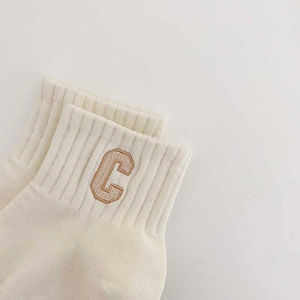 Creamy white crew socks with ribbed cuffs and brown embroidered letter C on a white background