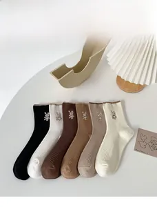 Flat lay of six cotton crew socks with rabbit embroidery in neutral earthy tones