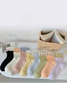 Detail of colorful ribbed crew socks with lettuce trim edge and delicate letter embroidery