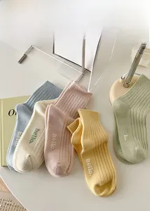 Close-up of ribbed cotton crew socks with hello embroidery in assorted pastel colors