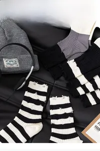 Detail of distressed knit socks with black and white stripes and unique frayed hole edges