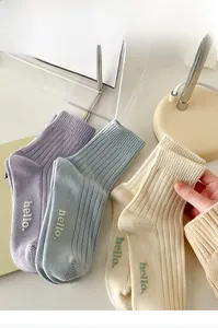 Detail of ribbed cotton socks with delicate hello embroidery in soft pastel tones