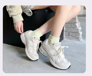 Close-up of light green cotton socks paired with cream retro athletic sneakers and N logo