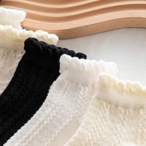 White and black knit socks with lettuce trim and delicate hollow jacquard textures