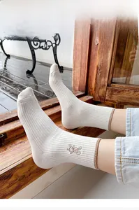 Detailed close-up of cream knit socks featuring brown contrast trim and cute bear embroidery