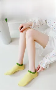 Close-up of yellow low-cut cotton socks with green trim and Smile embroidery detail