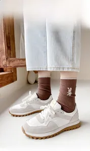 Close-up of brown ribbed cotton socks with white rabbit embroidery and retro sneakers