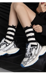 Close-up of distressed black and white striped crew socks with trendy chunky sneakers