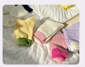 Detail of colorful rib-knit cotton socks in vibrant candy tones on white fabric
