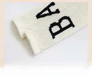 Gros plan sur des chaussettes en coton côtelé blanc avec broderie BA noire et tissu texturé