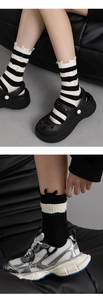 Detail showing distressed holes and black and white stripes on trendy mid-calf socks