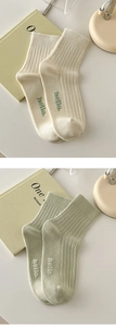 Detailed view of cream and light green ribbed crew socks with small hello text embroidery