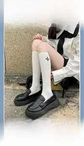 Detailed view of white cotton calf socks featuring black cross flower embroidery and loafers