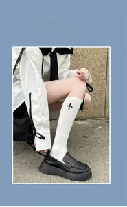 White calf socks with black cross embroidery paired with black platform loafers