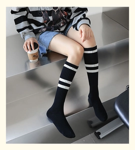 Détail de chaussettes hautes noires à rayures blanches portées par un mannequin