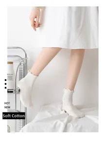 White cotton ruffled crew socks with ribbed texture worn by a model in a cozy setting