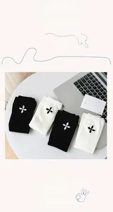 Detail of cotton knee-high socks featuring minimalist floral embroidery in black and white