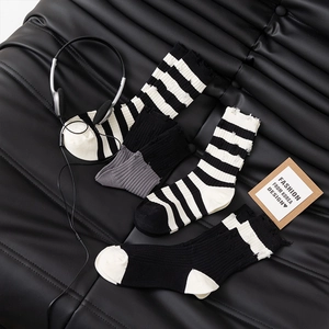 Set of distressed black and white striped crew socks with trendy street style hole details