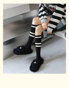 Gros plan de chaussettes en coton à rayures noires et blanches avec des pantoufles