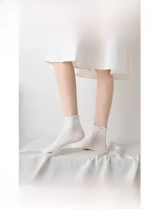 Close-up of white ruffle edge socks with ribbed texture and breathable cotton knit fabric