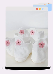 Détail de chaussettes basses en résille blanche avec broderie de fleurs de cerisier rose