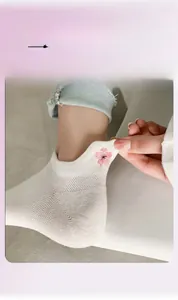 Détail montrant l'élasticité des chaussettes blanches en maille avec broderie cerisier