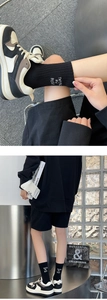 Detail of black cotton sports socks with white letter embroidery and sneakers