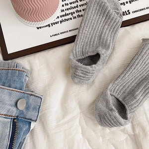 Grey ribbed open-toe and open-heel yoga socks for women on a white fabric background