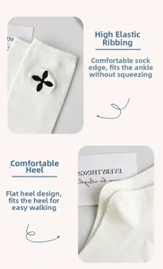 Detail of white knit calf socks with black flower embroidery and elastic cuffs