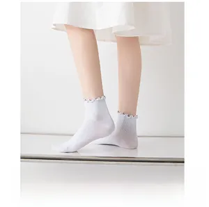 Detail of white cotton socks with lettuce edge cuffs and ribbed texture for women