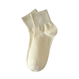 Solid cream cotton crew socks with ribbed cuffs shown in a minimalist flat lay composition