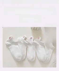 Détail de chaussettes invisibles blanches en coton avec broderie cerisier rose au talon
