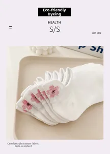 Gros plan de chaussettes en coton blanc avec broderie détaillée de fleurs de cerisier roses