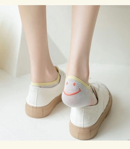 Gros plan de chaussettes en coton avec motif smiley orange dans des chaussures en toile