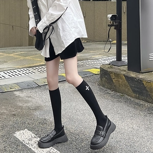 Women's black platform loafers with floral print knee-high socks for street style outfit